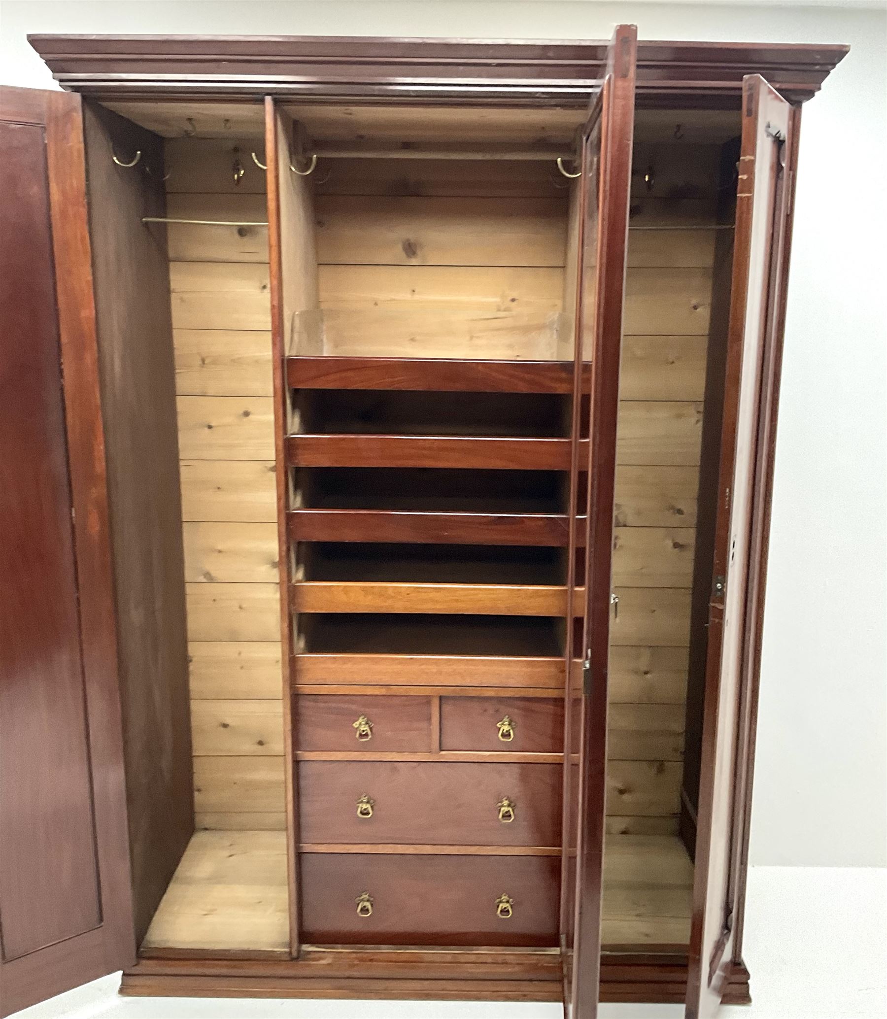 Victorian mahogany triple wardrobe, central mirrored door enclosing linen slides and two short and two long drawers flanked by two cupboards, plinth base