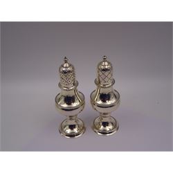 Modern silver two piece cruet set, comprising salt shaker and pepper shaker, both of waisted form with engraved rope twist borders, the removable pierced covers each with engraved lattice decoration, upon a circular spreading foot, hallmarked Laurence R Watson & Co, Birmingham 1989, H14.5cm, contained within velvet lined fitted case