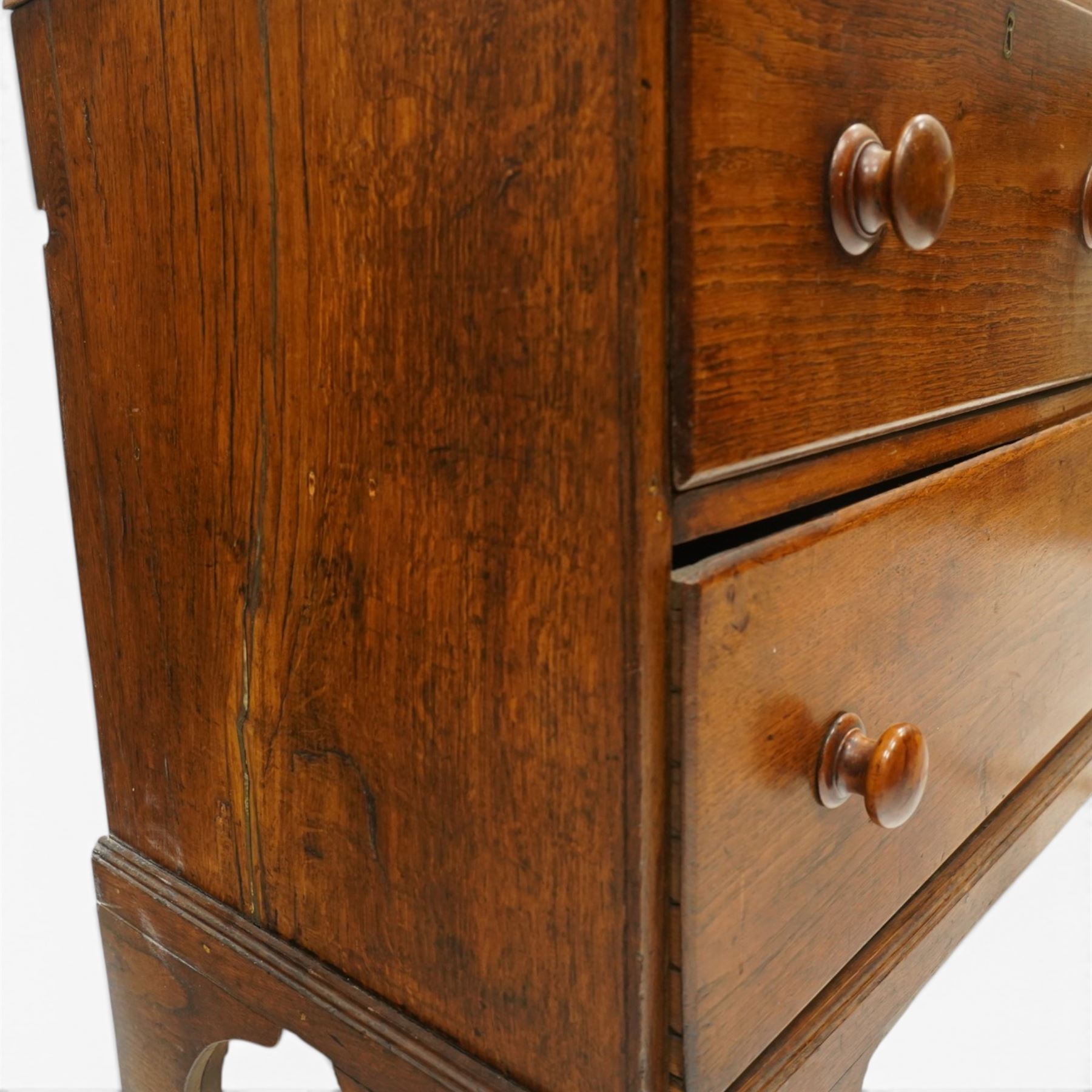 18th century oak larder cupboard, projecting moulded cornice over two panelled doors with shaped arched fielded panels, three short dummy drawers above base fitted with two short and one long drawer, turned handles, on bracket feet