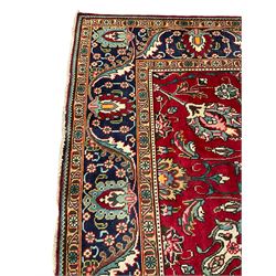 Large Persian Tabriz carpet, red ground field decorated with interlacing branch and trailing foliage, stylised flower head and plant motifs, the border decorated with stylised foliage motifs