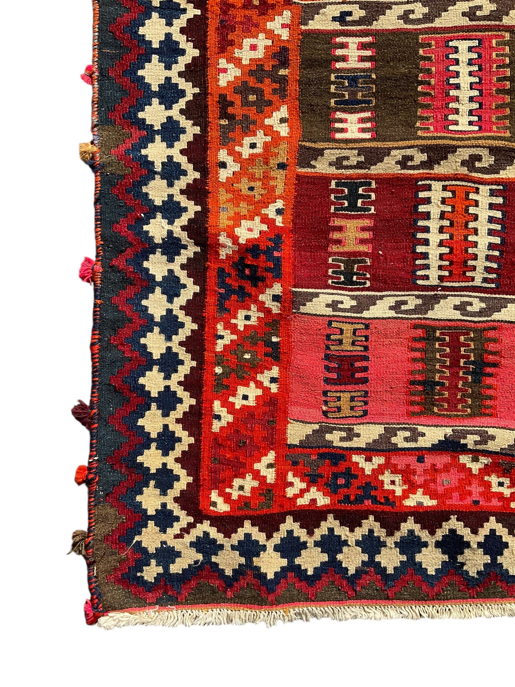 Southwest Persian Qashqai Kilim ground rug, featuring a series of horizontal striped panels each filled with intricate geometric designs, enclosed by a dark blue and ivory border with stylised star and zigzag motifs