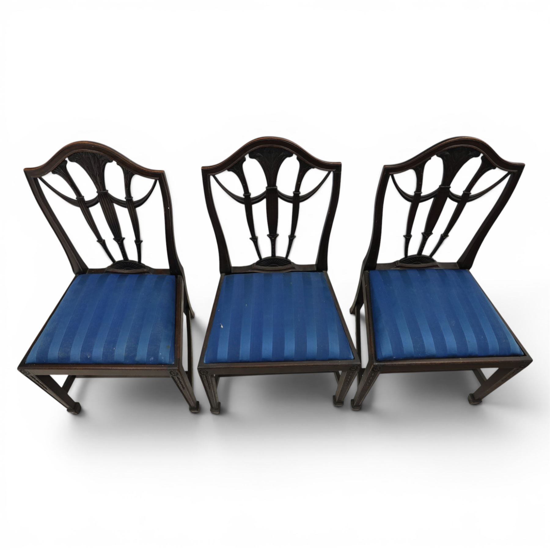 Set of eight George III style mahogany dining chairs, comprising two carvers and six singles, each with shaped top rail above pierced splay carved with feathers, with drop in stuffover seats upholstered in blue striped fabric, raised upon square tapering legs joined by stretchers, together with a mahogany twin pedestal dining table, the oval top with central leaf raised upon turned columns and splayed reeded legs terminating in lion paw feet and brass castors, 