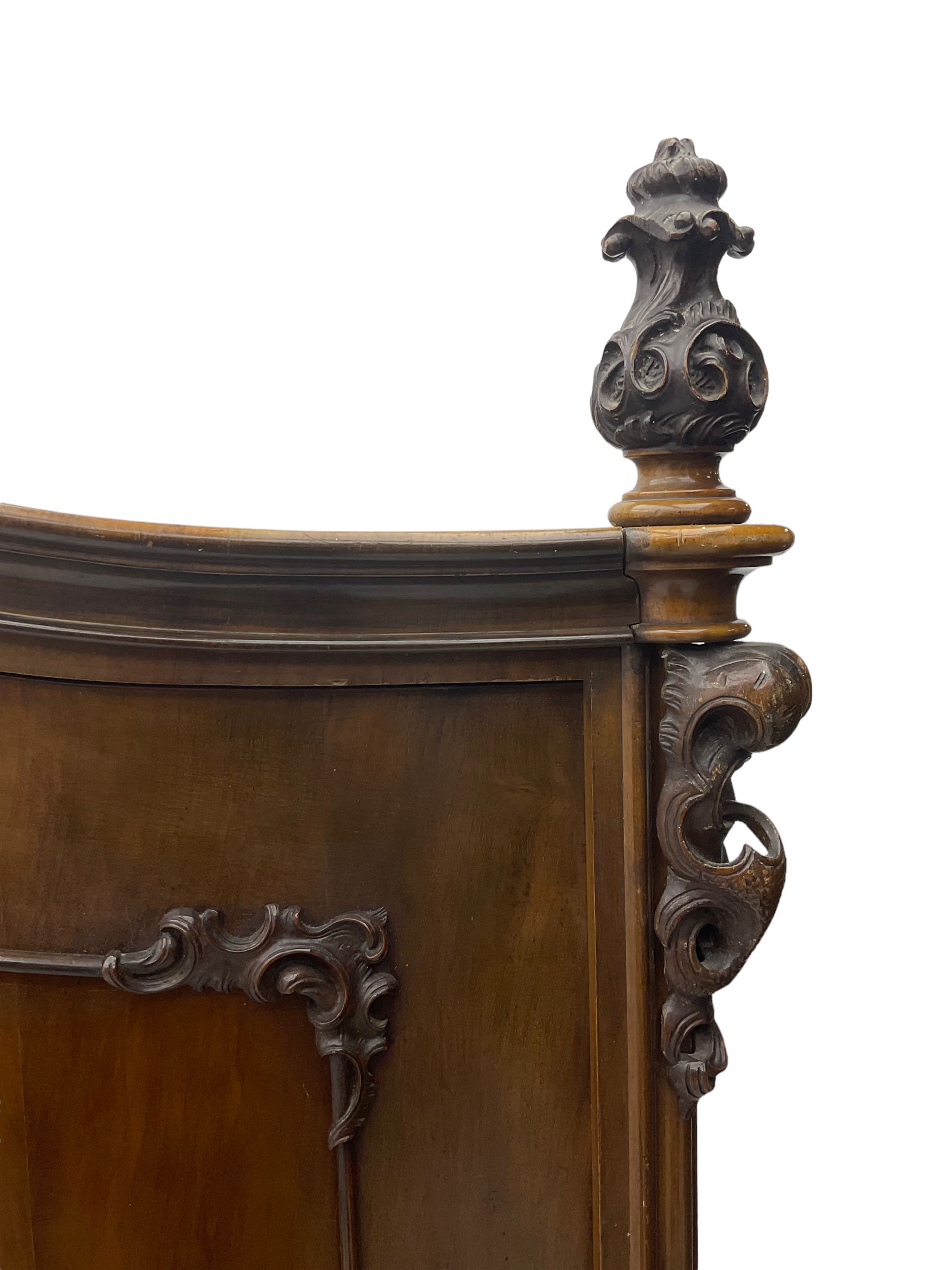 Early 20th century Italian walnut armoire wardrobe, the pierced and scrolling pediment carved with acanthus leaf detail, flanked by two scrolling cartouche with matching corbels below, the two panelled doors with applied carved rinceaux slips, with a central spiral turned upright, enclosing single shelf and hanging rail, raised on scroll feet