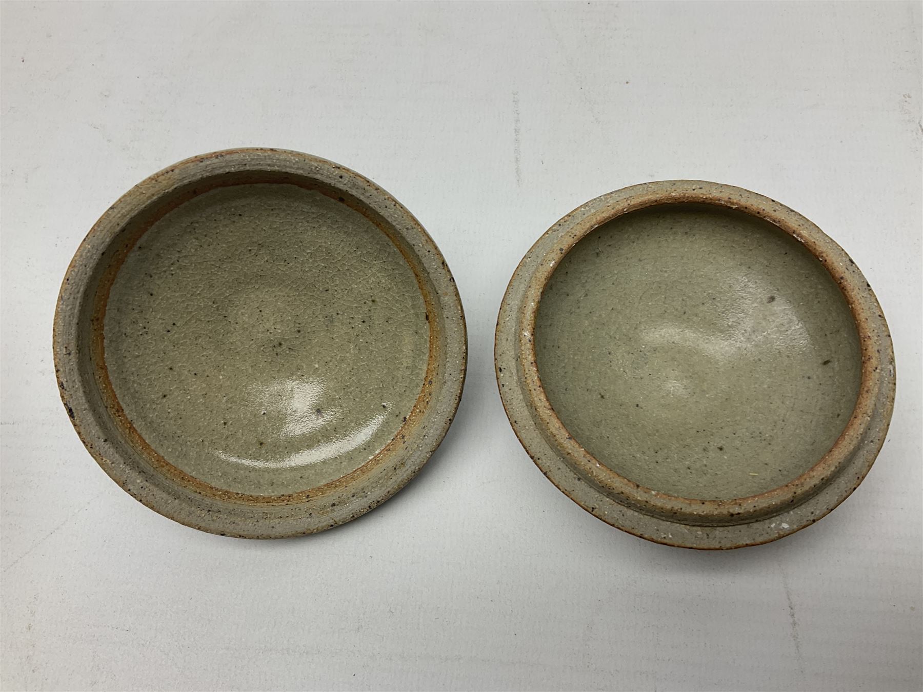 Janet Leach (American, 1918-1997) for Leach Pottery; speckled studio pottery vase of shouldered ovoid form with speckled brown decoration and trailing green and brown glaze upon beige and brown ground, with impressed J.L. monogram and Leach Pottery mark beneath, together with a Jeremy Leach blue speckled lidded circular dish with loop handle, impressed J.L, tallest H11cm