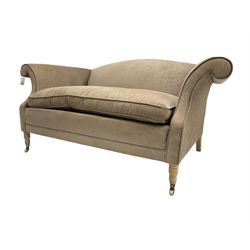 Traditional two seat sofa, curved back over scrolled arms, upholstered in crushed beige fabric with matching loose cushions, on turned front supports with brass and ceramic castors