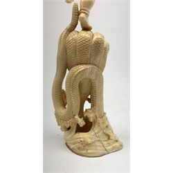 A large Japanese carved ivory okimono, modelled as a figure stood upon one leg with arms outstretched, upon a five headed serpent emerging from waves, H30cm.