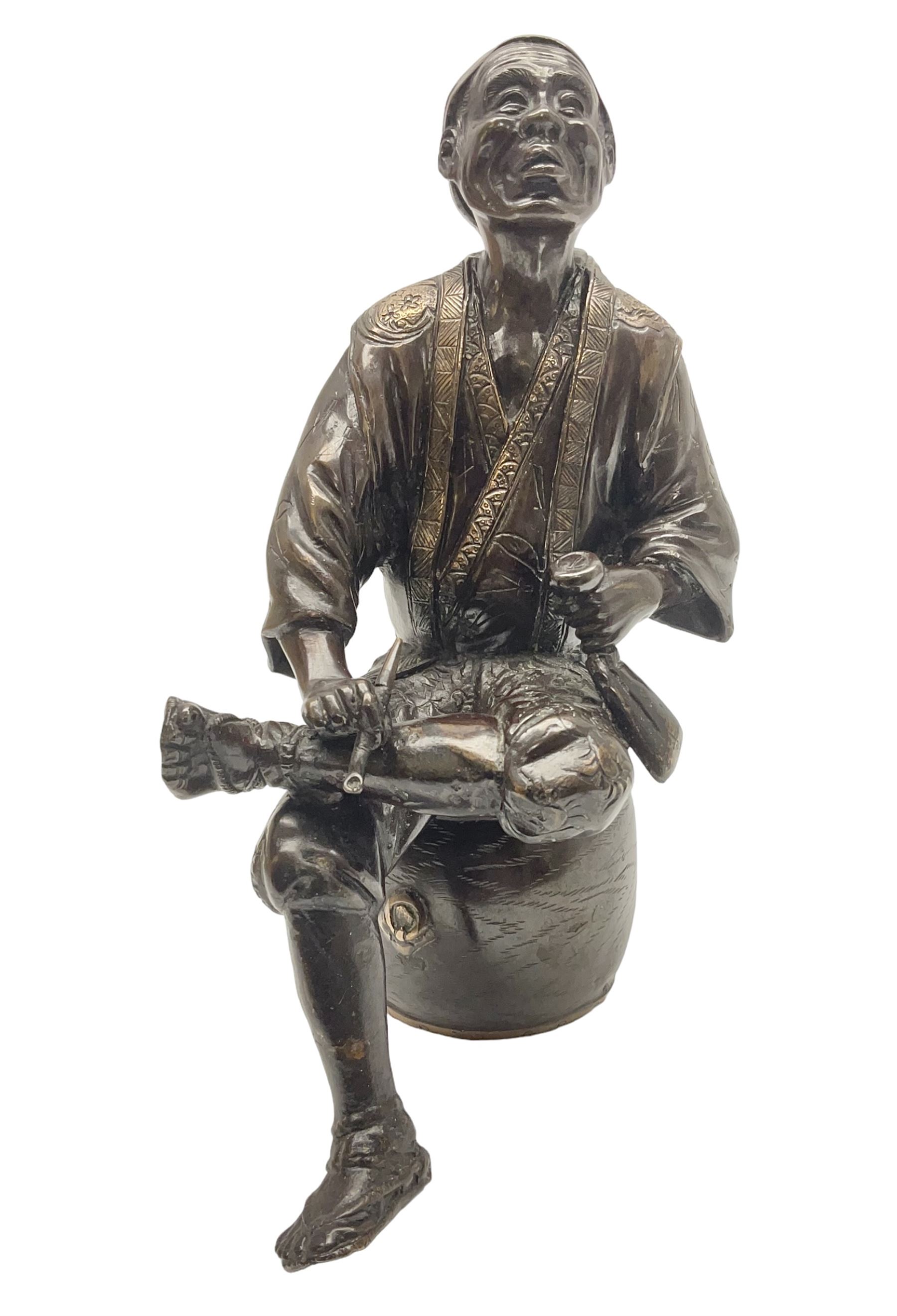Oriental bronze figure of a gentleman, modelled seated upon barrel with a pipe in one hand and a flask in the other, H21cm