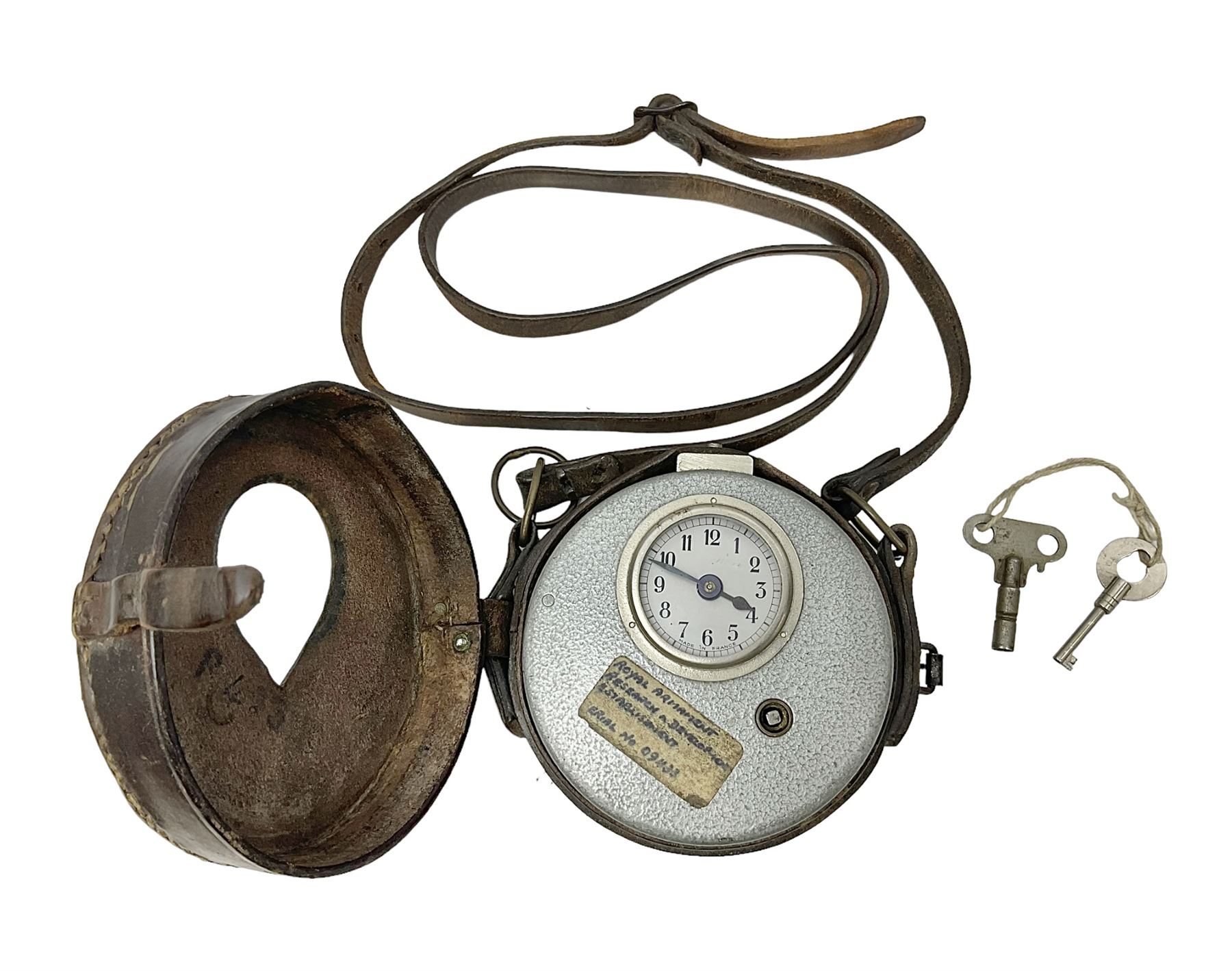 Metal cased drum shaped travelling clock with grey hammered finish, French clockwork movement and stitched leather outer case with shoulder strap; bears manuscript label 'Royal Armament Research and Development Establishment - serial no.09433' D13cm overall