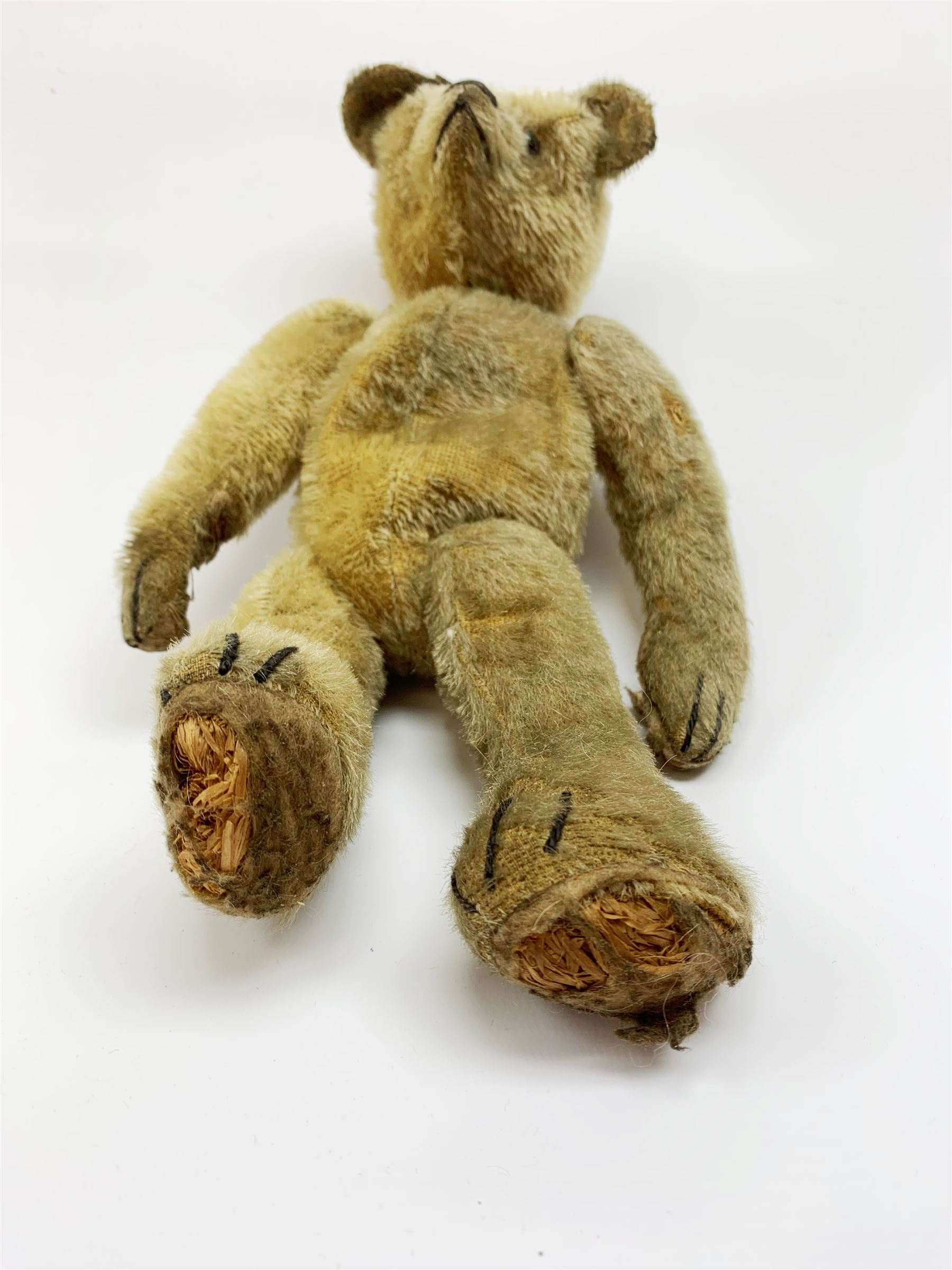 Early 20th century American mohair teddy bear c1920 with wood wool filled body humped back body with jointed limbs, black boot button eyes and horizontal stitched nose and mouth H12