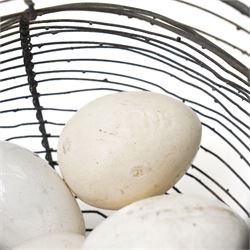 Two wire crocks, each containing 11 broody hen ceramic dummy eggs, four marked 'Caperns'