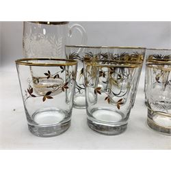 Mid 20th century glass part lemonade set comprisimg jug decorated with white floral sprays and gilt banding with three matching cups, together with a set of six tumblers decorated in black and gilt with flowers and set of four other glasses