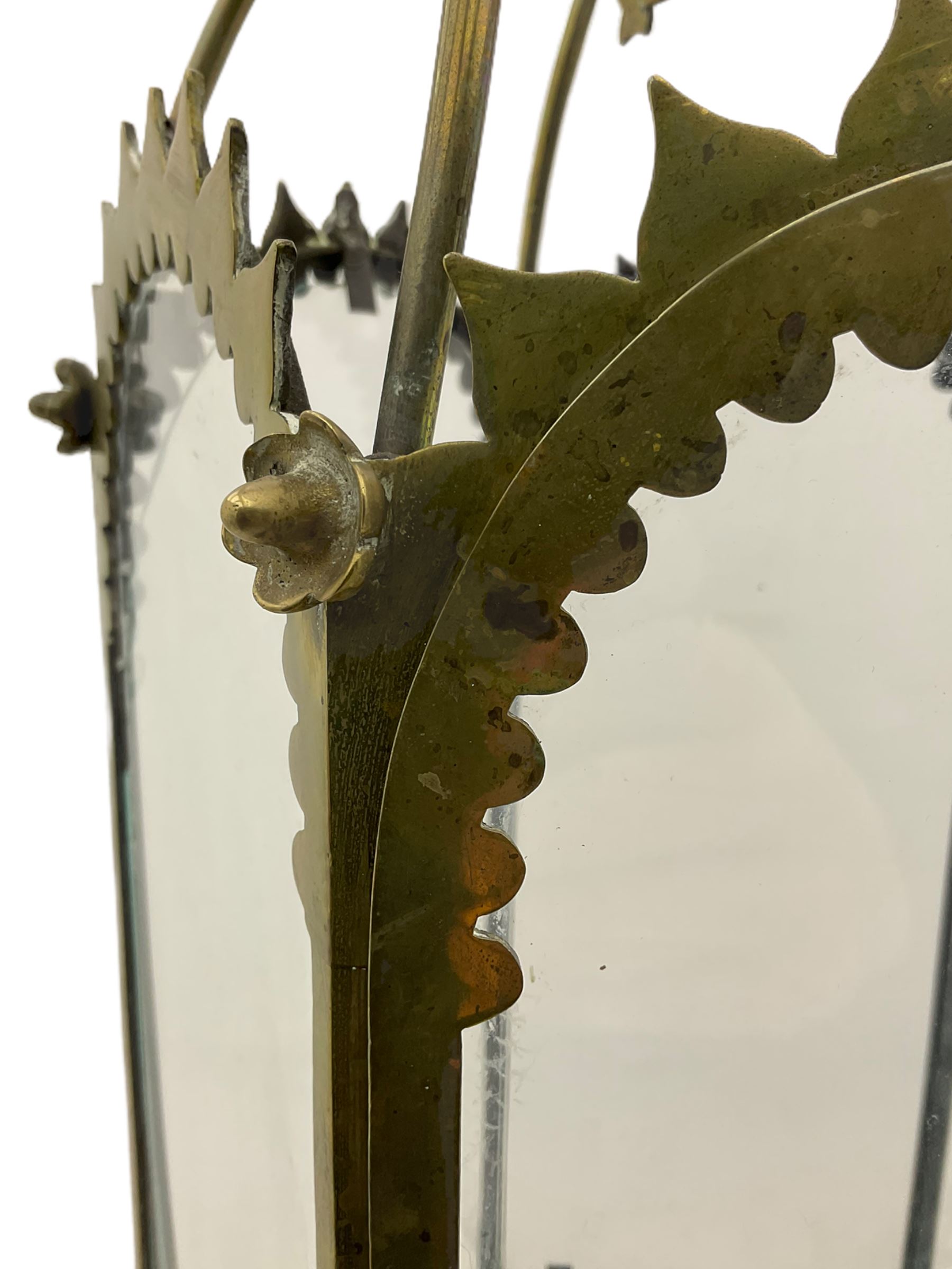 19th century brass and clear glass hexagonal hall lantern, with scrolling wire work open domed top over six arched panels, including a hinged door, the base enclosed with a circular glass panel on turned feet, H64cm