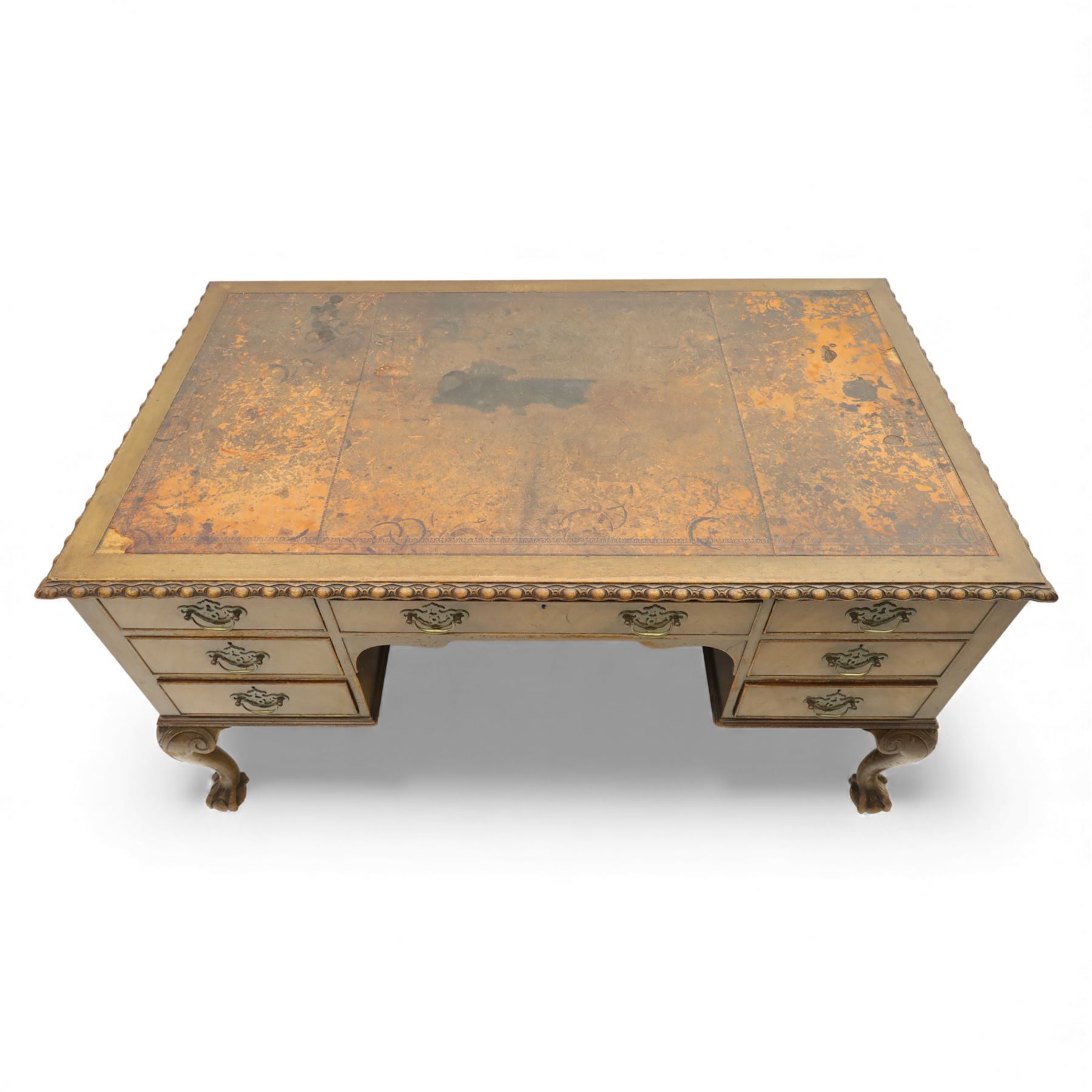 Waring & Gillow - Early 20th century mahogany desk, the leather-inset top above a shaped kneehole, central compartmented frieze drawer flanked by twin banks of of three drawers, each with brass handles, raised on cabriole legs with carved ball and claw feet (Height from floor to underside 62cm)