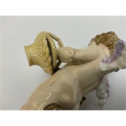 Late 19th/early 20th century Meissen figure of cupid, modelled standing with empty quiver across back, holding a basket in one arm, the other raised to head, upon a naturalistically modelled base detailed with gilt bow,  and marble effect socle base with gilt bands, with blue crossed swords mark beneath, H18.5cm