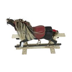 20th century black painted rocking horse on white painted trestle base, fitted with saddle and stirrups 