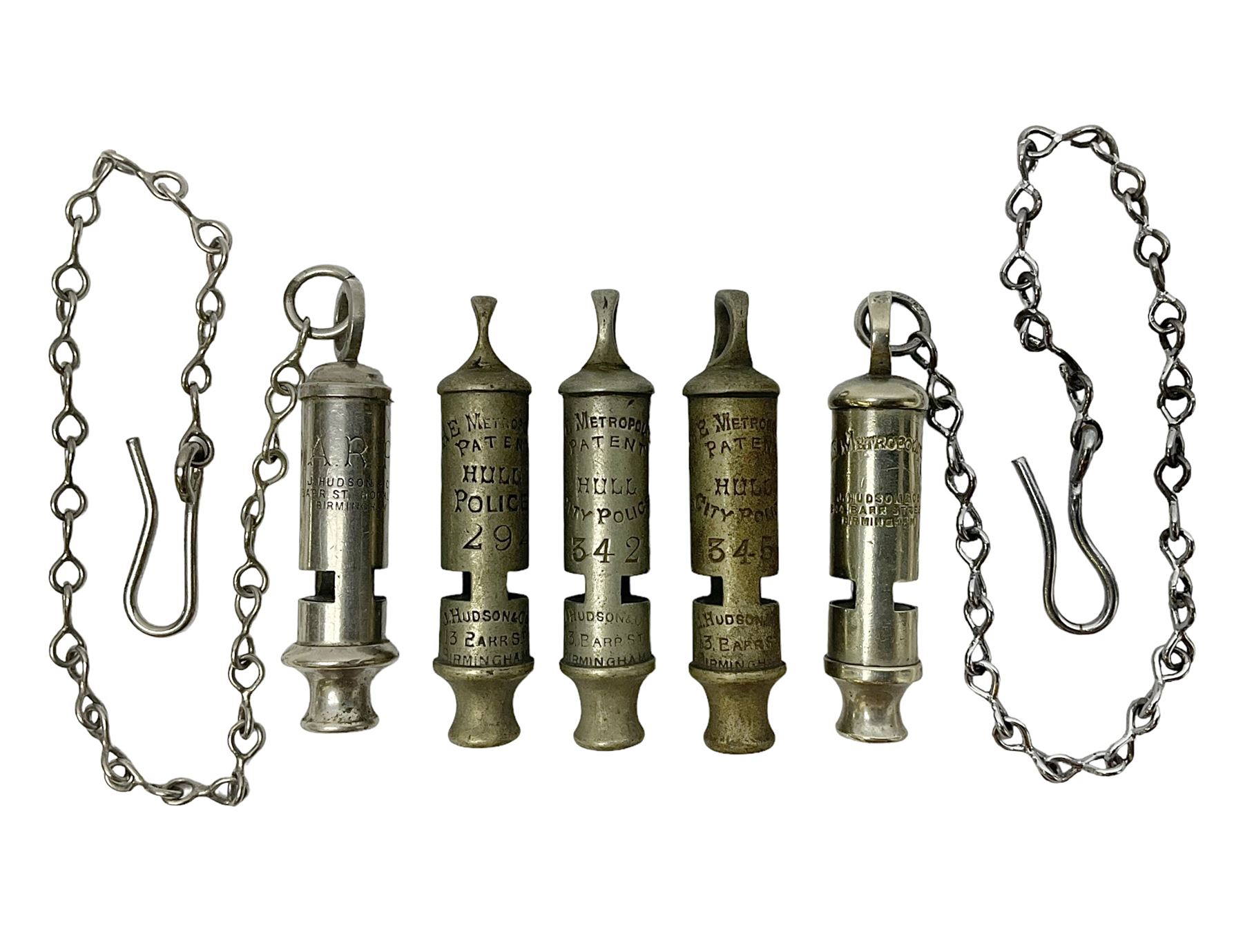 Three Hull City Police 'Metropolitan' whistles by J. Hudson 13 Barr Street Birminham, each with impressed collar number; another 'Metropolitan' police whistle with chain; and an ARP whistle by Hudson & Co with chain (5)
