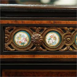 Victorian Aesthetic Movement amboyna and ebonised cabinet, the arched raised back inlaid with amboyna and floral porcelain plaque, over a raised shelf with fluted and turned supports, and a bevelled mirror plate with brass beading beneath, the inverted-breakfront top over an ornate frieze drawer with guilloche style gilt-metal mounts and porcelain plaques, the panelled door with a central porcelain plaque depicting a lady in a fuchsia gown within concentric ebonised and amboyna inlays, flanked by architectural style uprights with Corinthian capitals, raised on turned feet