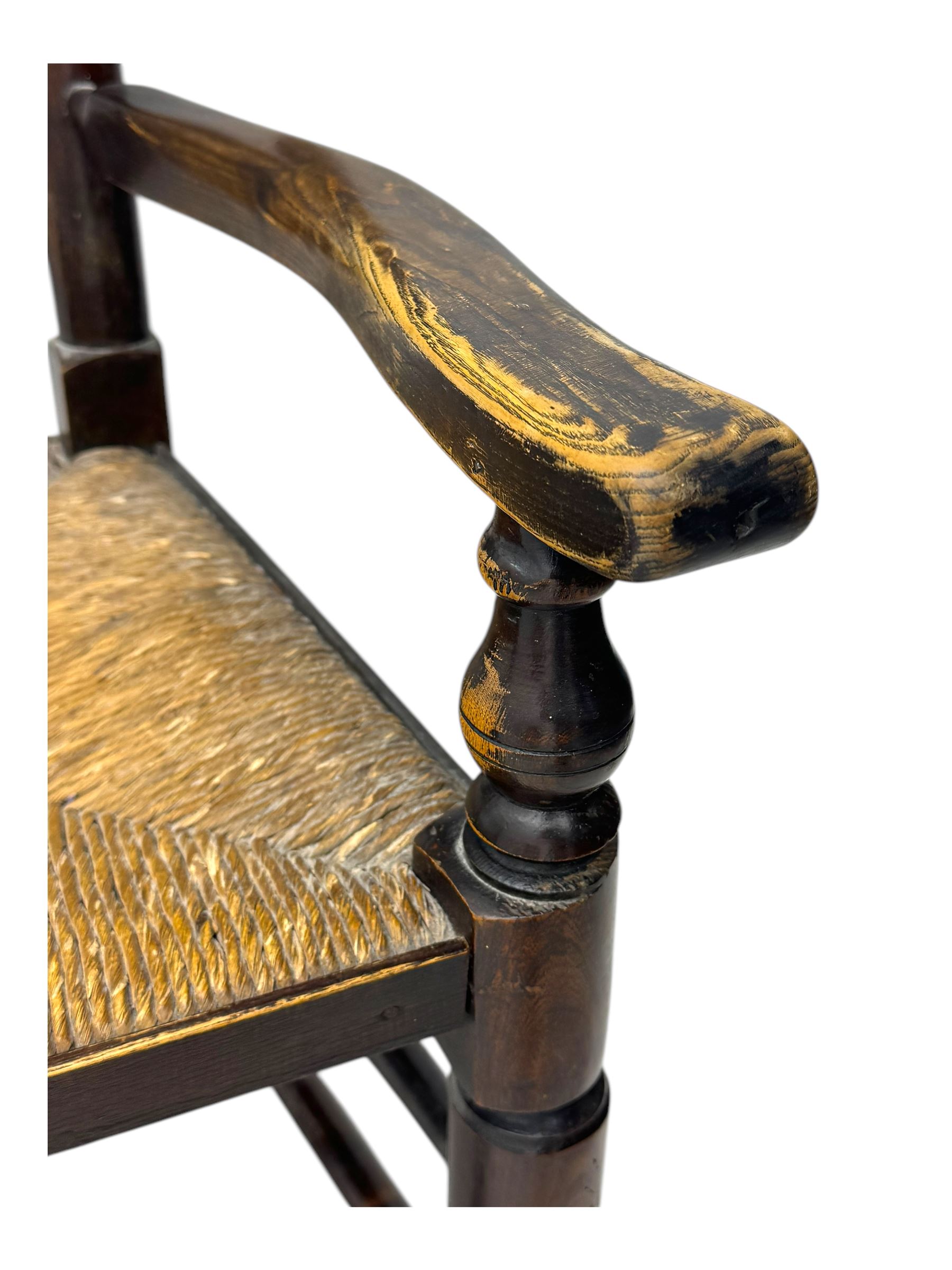 Early 19th century ash armchair, the back with winged spindles extending from a shaped top rail, above a splat of two rows of vertical spindles, with curved arms and a rush seat, raised on turned supports united by double stretchers terminating in castors