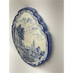 A 20th century Delft style blue and white faience pottery plaque, of shaped form decorated with a riverside scene, H36cm L32cm.