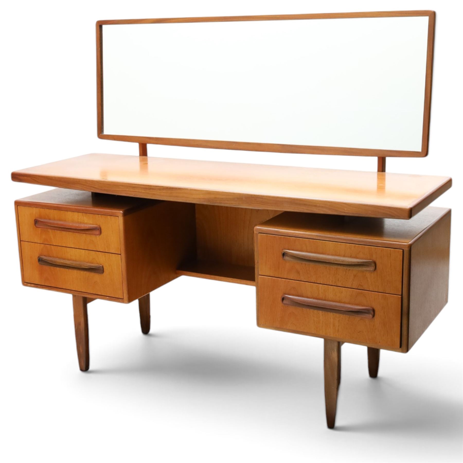 G-Plan - ‘Fresco’ teak dressing table, rectangular top with raised rectangular mirror, fitted with four drawers arranged as twin pedestals with sculpted handles, central knee-hole, on tapering supports