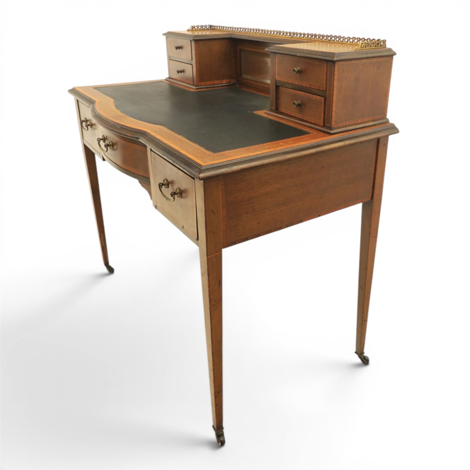Maple & Co - Edwardian mahogany inlaid writing desk, the superstructure with pierced brass gallery, above an inset mirror and two short drawers, inset leather writing surface, bow fronted with crossbanded drawers and brass swan neck handles, square tapering supports terminating in castors 