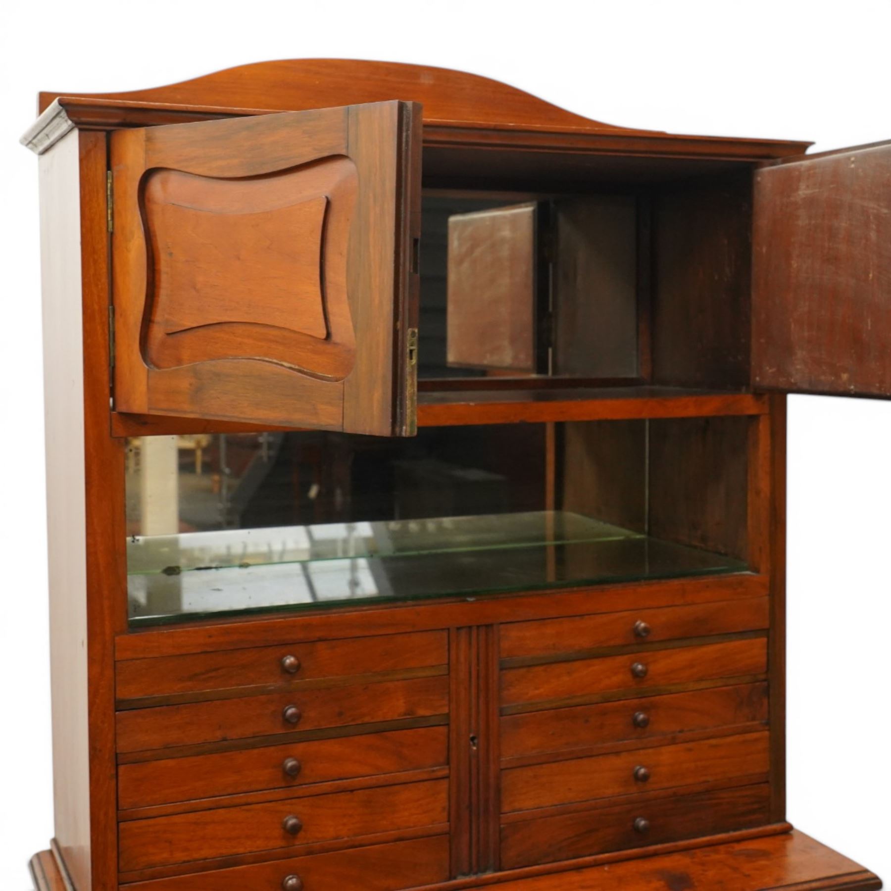 19th century walnut dentist cabinet, galleried top above twin cupboard doors with mirrored interior, recessed mirrored section, two banks of five graduated drawers, shaped section with brushing slide above a fall front, two short drawers and twin cupboard doors, on a plinth base 