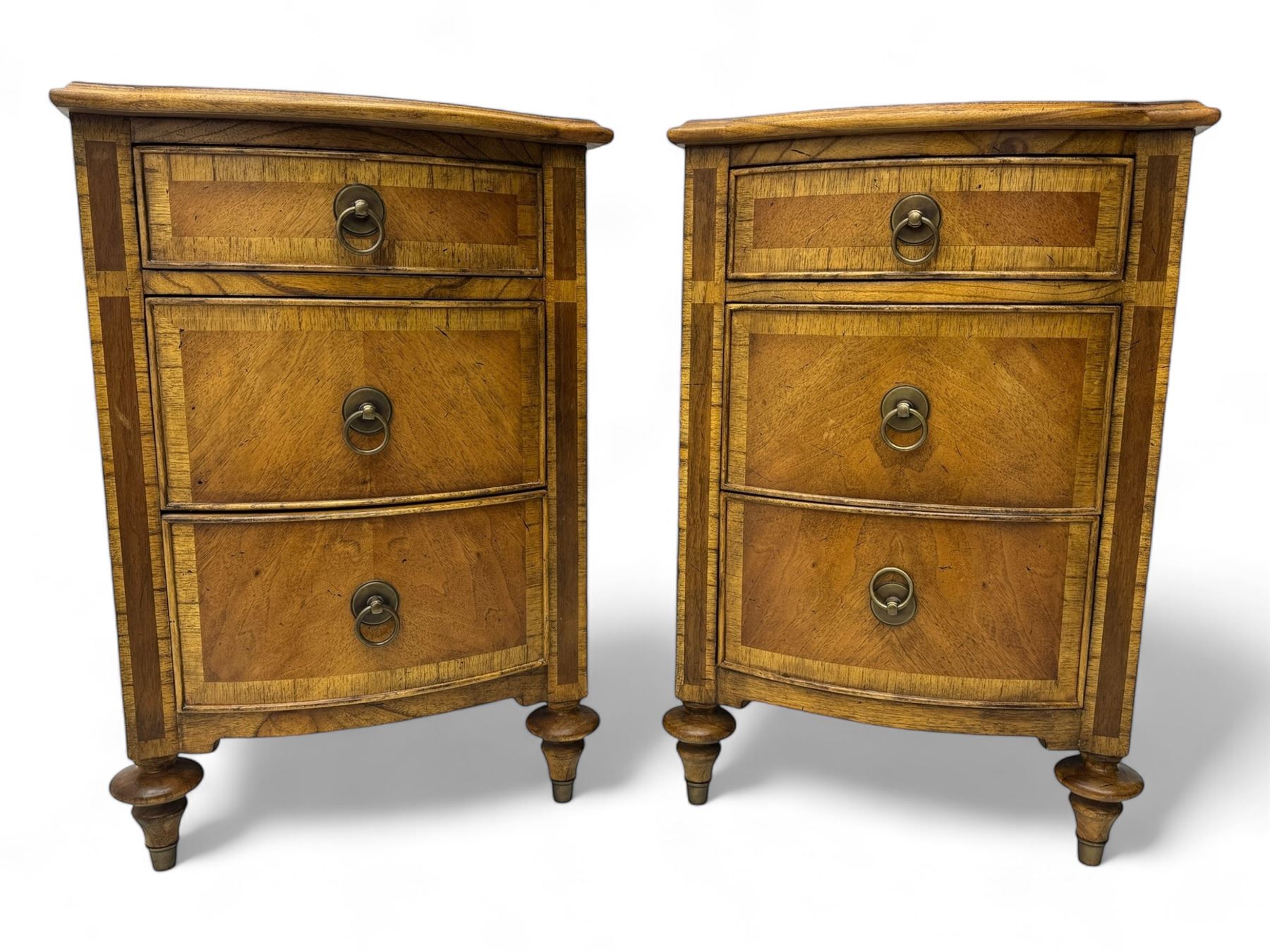 Frank Hudson - pair of mid-20th century Mindi ash and burr walnut bedside chests, bow-fronted and crossbanded top over three graduated drawers, on turned supports