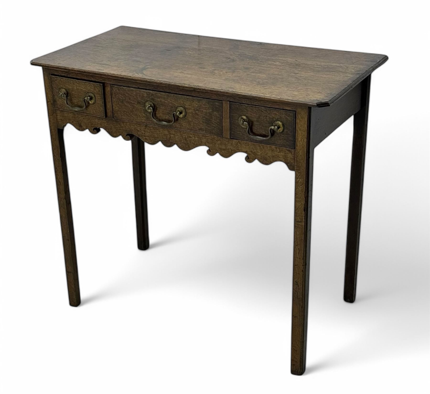 18th century oak lowboy, rectangular moulded top over three frieze drawers with brass swing handles, scalloped apron, on slender square section supports