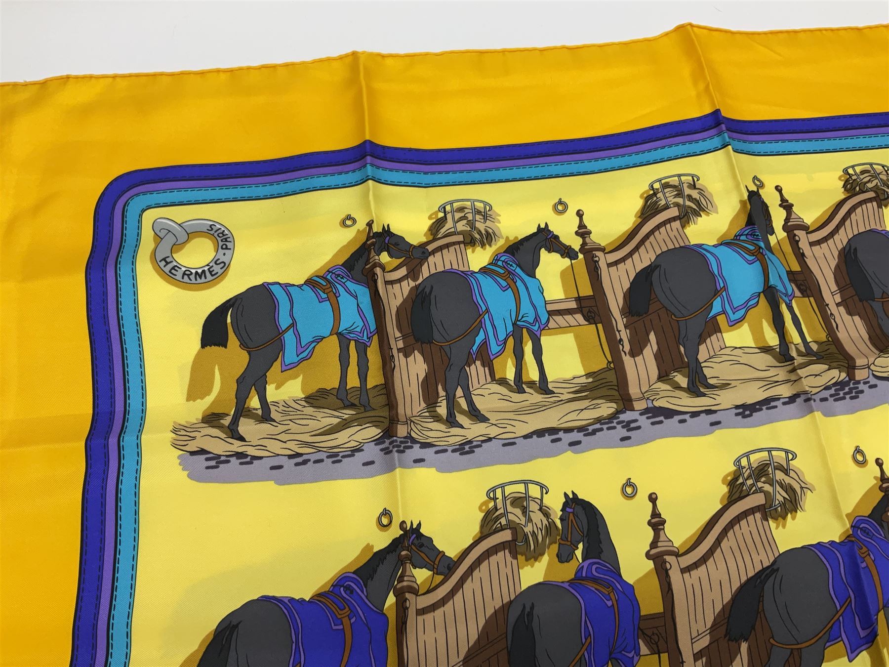 Hermès 'Ecuries' silk scarf, designed by Hugo Grygkar in 1947, printed with twenty horses in their respective stables, on yellow ground contained within stitched effect blue and purple and darker yellow gold borders, with rolled hand stitched edges and Hermes material label, 87cm square