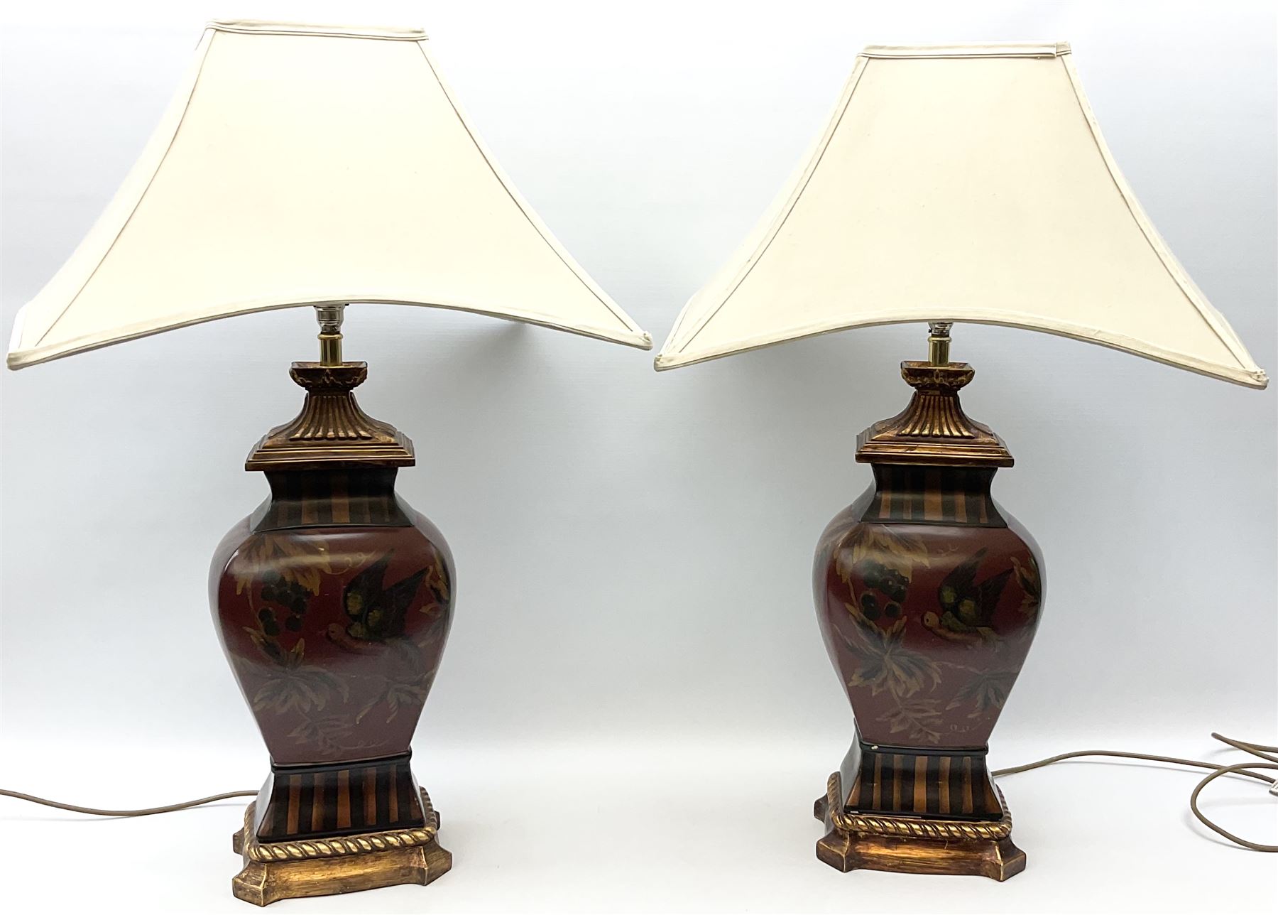 Pair Oriental table lamps decorated with birds in a tree with fruit, on a red ground with a gilded base together with cream lampshades H57cm, without lampshade. 