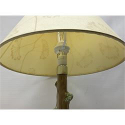 Nao table lamp modelled as a boy playing the flute upon logs with two recumbent sheep at his feet, the stem modelled as a tree trunk, with fabric shade, with printed mark beneath, H46cm