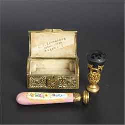 Gilt bronze mounted black glass seal, contained within a brass casket, with velvet interior and inner label reading 'C. F. Schmedding Augsburg', together with a porcelain handled seal decorated with floral sprays on a pink ground