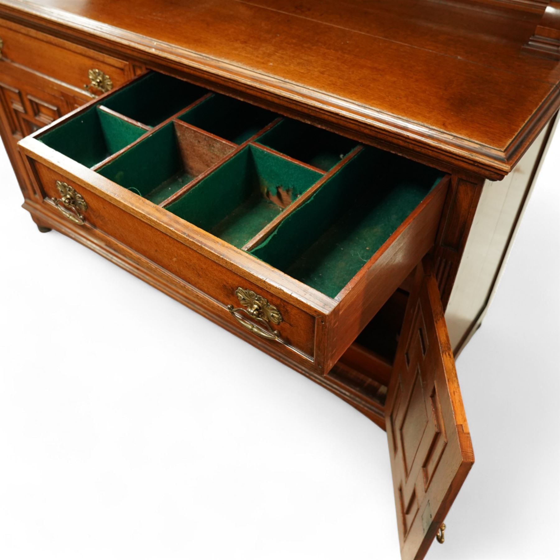 Early 20th century golden oak dresser sideboard, superstructure with three stained and leaded glass doors flanked by carved uprights above an open display shelf, the base with three drawers and geometric panelled cupboard doors, enclosing drawers with cutlery and bottle compartments, raised on short feet
