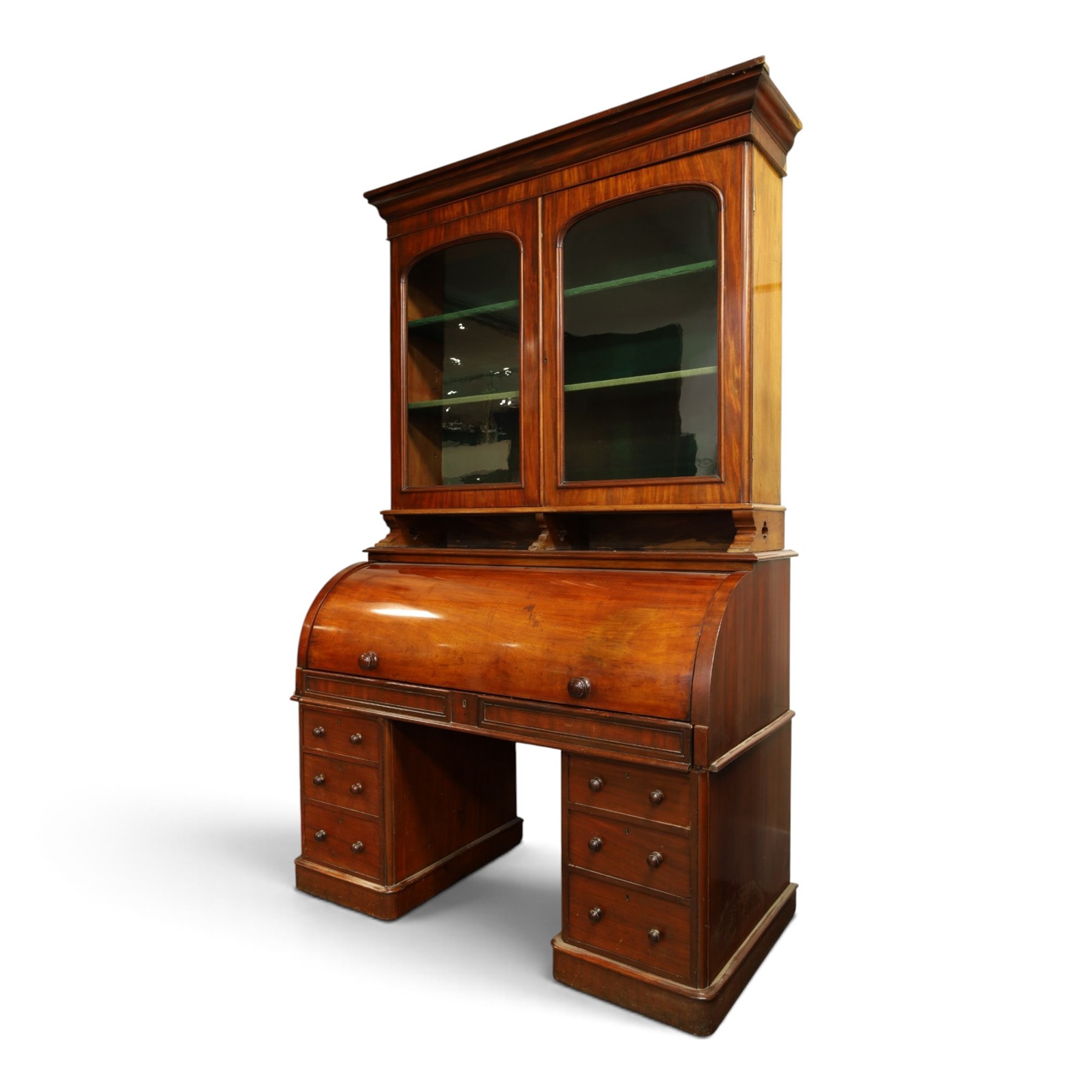 Victorian mahogany cylinder roll-top bookcase-secretaire, projecting cornice over twin glazed doors enclosing two shelves, the cylinder roll-top enclosing fitted interior with sliding drawer, hinged compartments, correspondence drawers and pigeon-holes, the twin pedestals fitted with three graduating drawers to each side, on plinth bases with castors