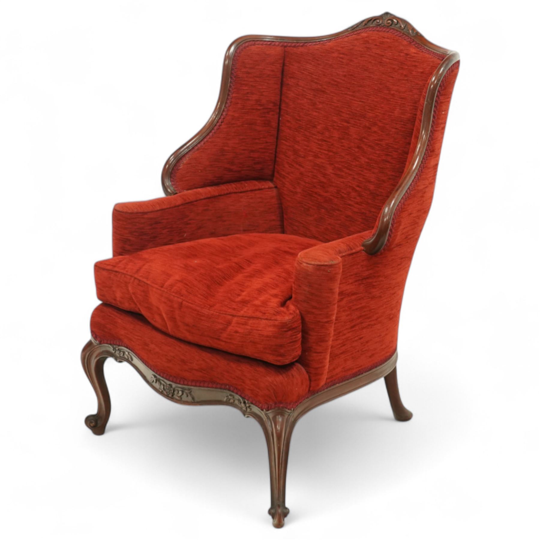 19th century Rococo revival upholstered armchair, red textured fabric over a carved walnut frame, shaped back and sides, floral carved serpentine seat rail, on cabriole supports 