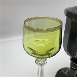 19th Century Bohemian amethyst glass lidded goblet, the bowl of faceted form, gilded with three children in period dress playing games, upon a knopped stem and conforming faceted foot, together with an art nouveau green glass goblet, with gilded rim, upon clear trumpet stem, and a hand blown wine glass, transfer printed with birds and three figures in period dress, tallest H29cm