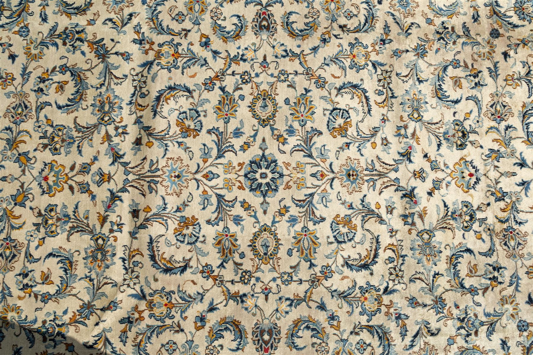 Central Persian Kashan hand-knotted carpet, ivory field profusely decorated with an all-over scrolling vine, palmette, and lotus design in shades of soft blue, pale gold, and green within floral borders