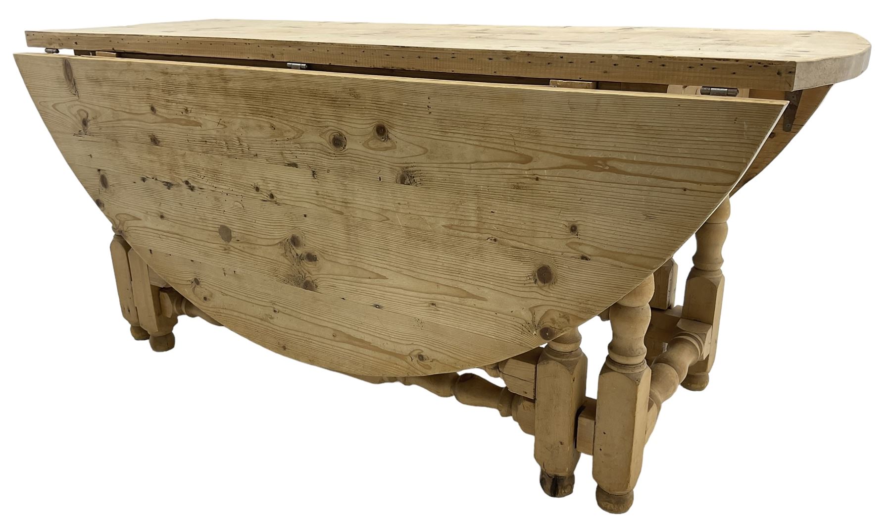 Traditional stripped pine dining table, circular drop-leaf top over double gate-leg action base with turned supports united by turned stretchers