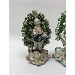 Near pair of bocage figures, the first an 18th century Derby example modelled as a young boy holding flowers, upon a gilt detailed scrolling base, with patch marks beneath, H17cm, together with a later example in the Chelsea-Derby style modelled as a young girl holding flowers, upon similar base, H18cm