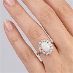 18ct gold opal and diamond cluster ring, single oval cabochon cut opal, surrounded by fourteen round brilliant cut diamonds, London 1988, total diamond weight approx 0.30 carat
