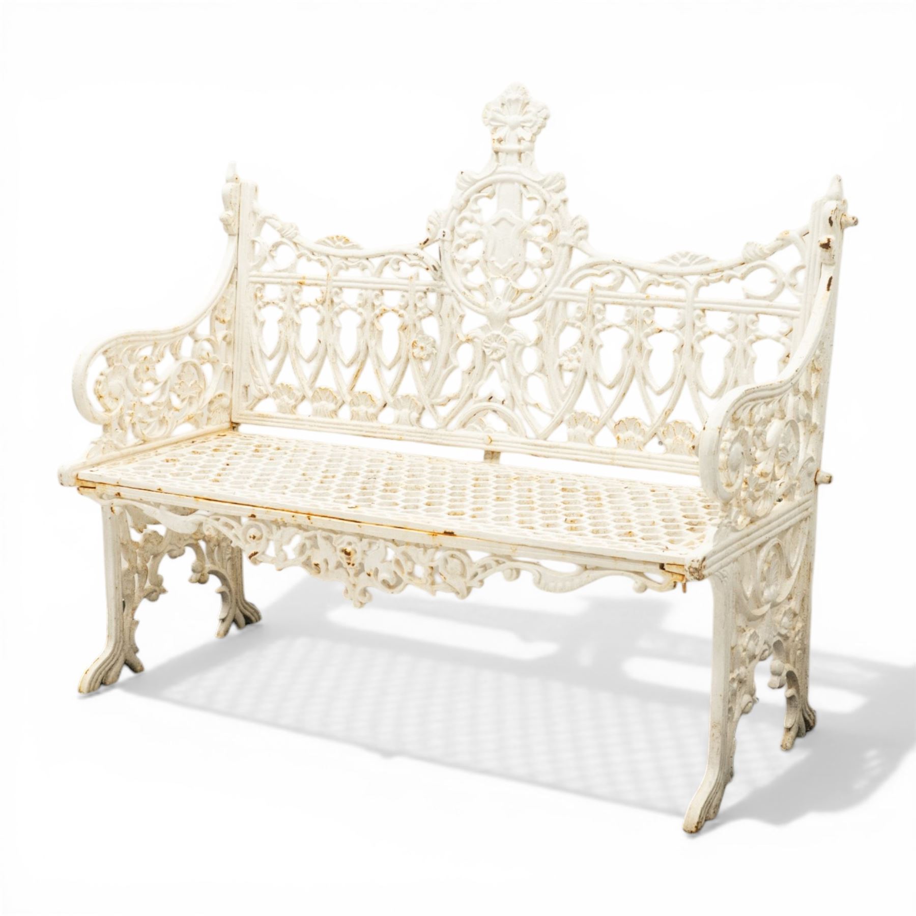 Victorian revival heavy cast iron garden bench, ornate back rest with scrolls, floral motifs and central crest, pierced lattice seat, curved arms and decorative legs, painted in antique white, in the Gothic Coalbrookdale style
