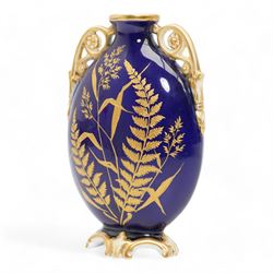 Early 20th century Royal Worcester loving cup, circa 1906, painted with a view of the River Severn and flowers to the reverse, H13cm, Grainger & Co. Worcester twin handled vase, the oval body painted in the Aesthetic style with ferns and grasses in gilt, against a cobalt blue ground, with scrolled handles and quatrefoil foot, H17cm (2)
