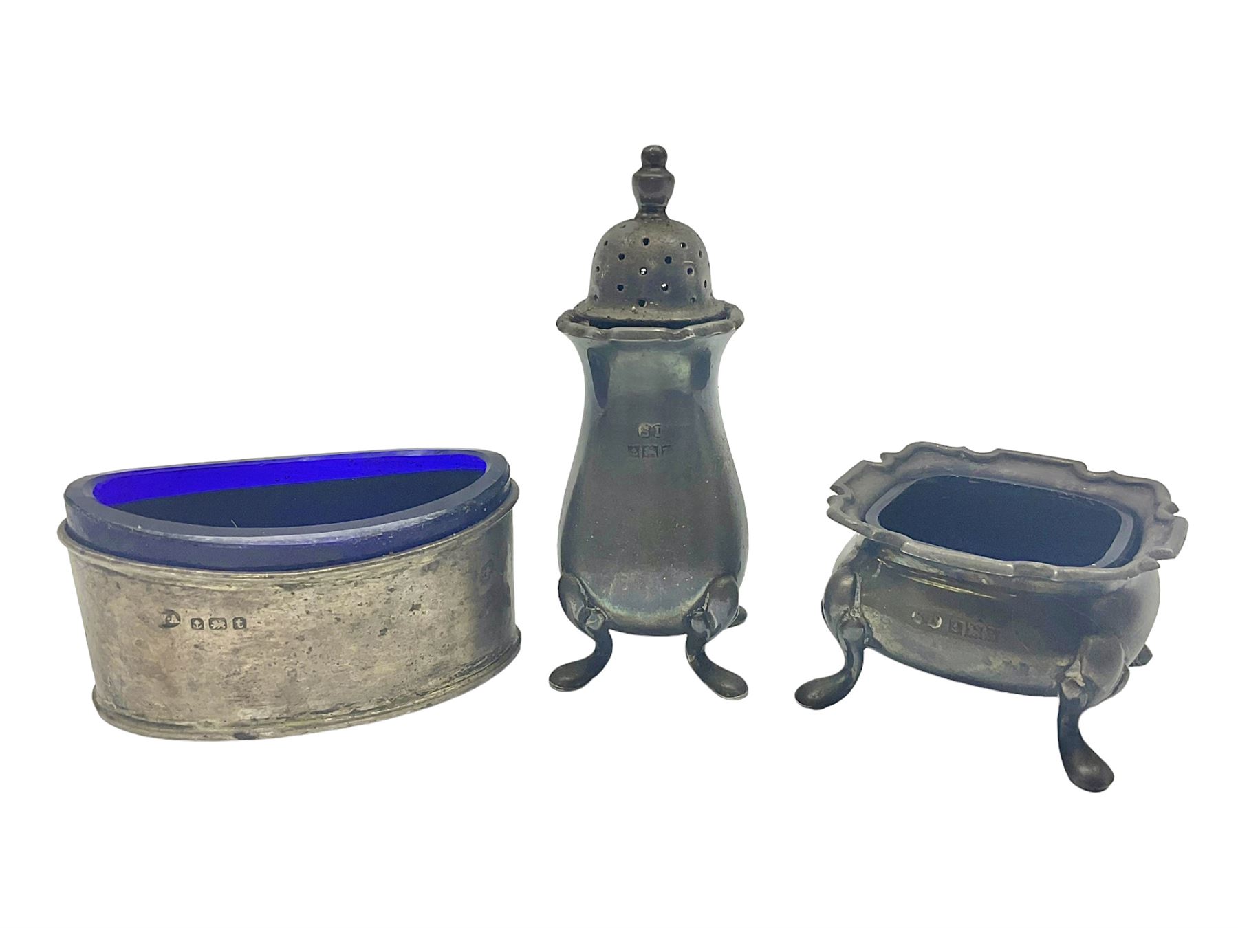 Modern two piece silver cruet set, comprising pepper shaker and open salt, each with shaped rims and upon four pad feet, hallmarked William Suckling Ltd, Birmingham 1962, together with an early 20th century silver open salt, of oval form, hallmarked William Aitken, Birmingham 1918
