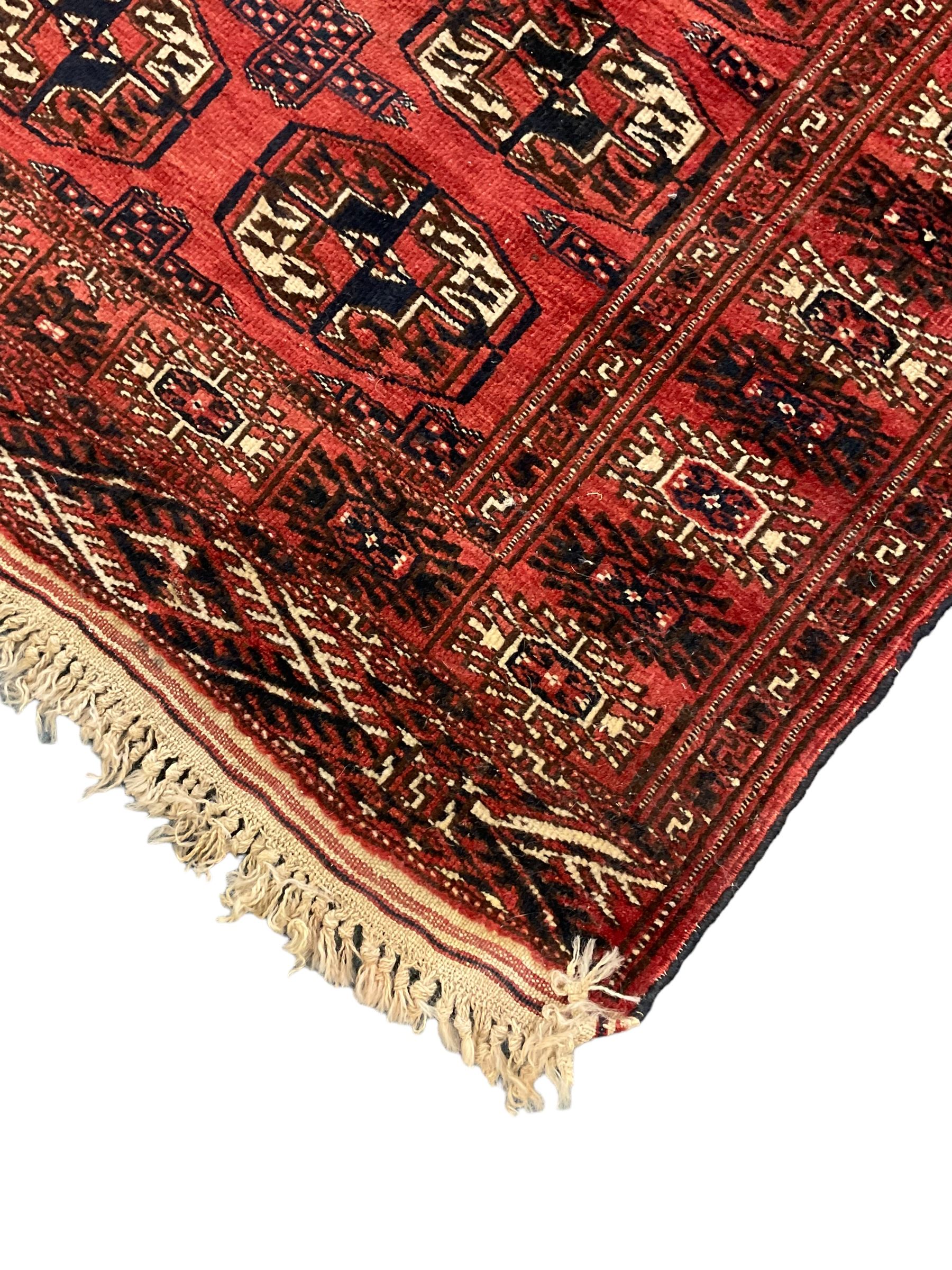 Bokhara red ground rug, decorated with two rows of Gul motifs, the border with geometric guard bands decorated with stylised plant motifs