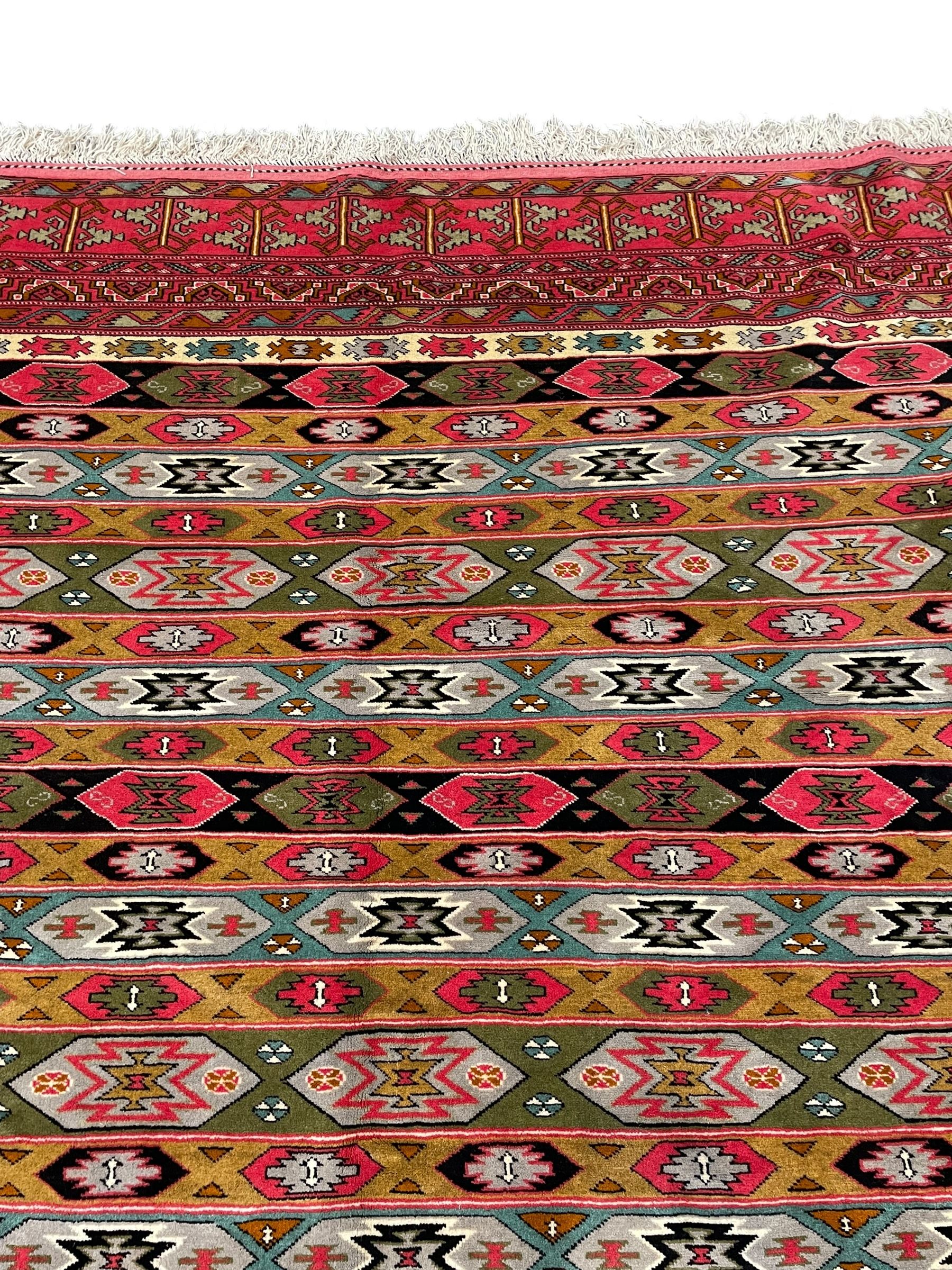 Persian red ground rug, the field divided into horizontal rows and decorated with geometric motifs, intricately pattern borders and end panels