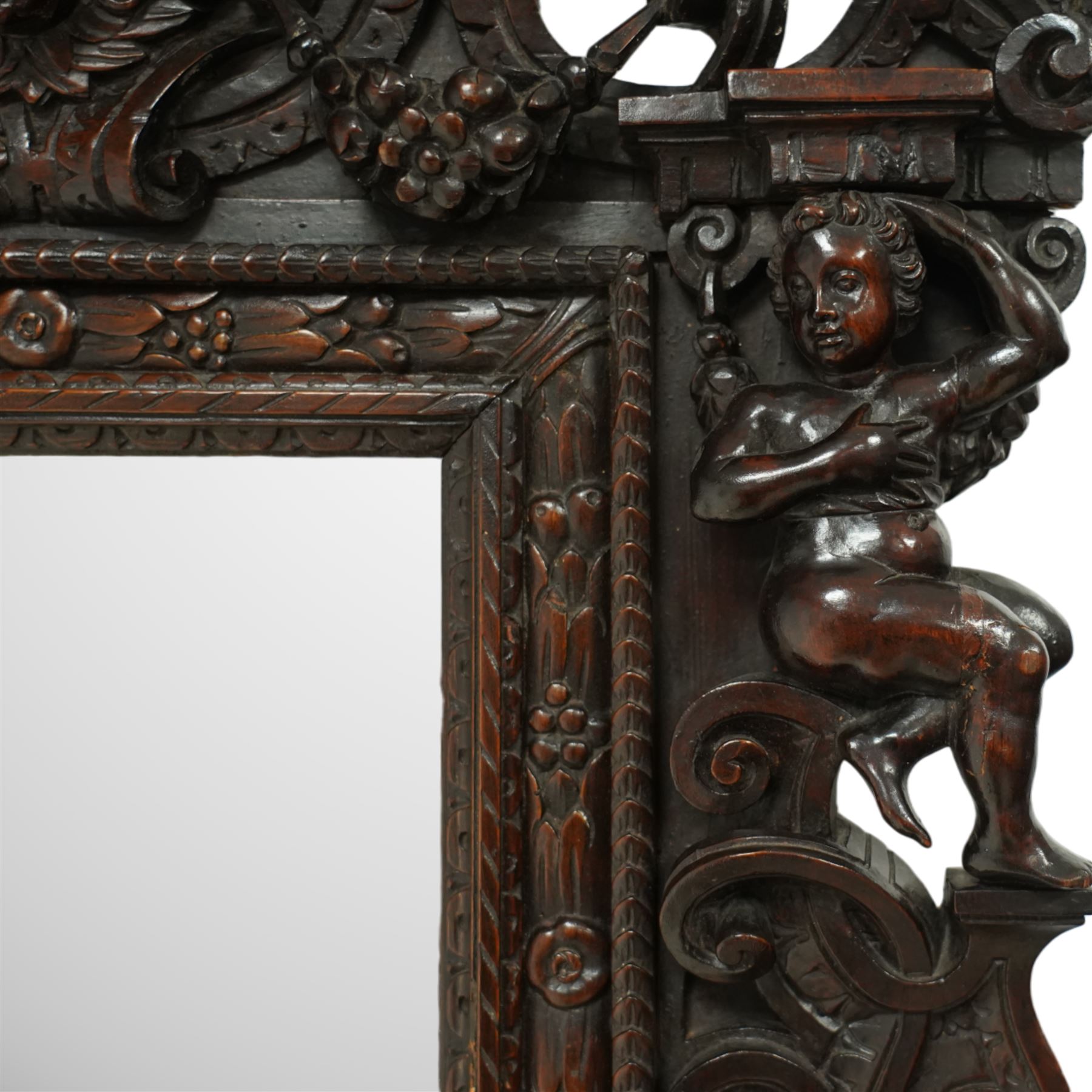 Renaissance-style mid 19th century carved fruitwood wall mirror, carved top surmounted by ‘broken’ arched pediment with central putti figure and grape vine, the sides with two putti figures above C-scroll decorations, and with a similarly carved base