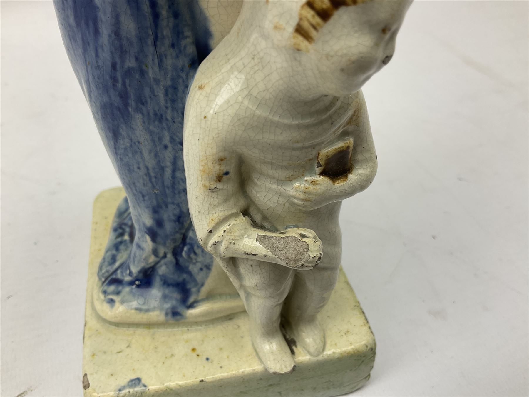 Late 18th century Prattware figure representing Charity, modelled as a mother with baby in her arms and two small children clutching at her robes, upon a square base, overall H21cm.