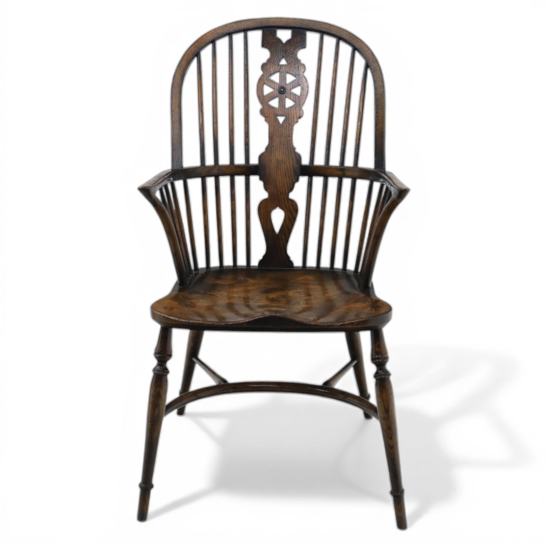 Late 19th century elm and beech high back Windsor armchair, the arched hoop back centred by a pierced wheel splat above a heart shaped lower piercing, with turned spindles and shaped arm rail, saddle seat, raised on turned legs united by a crinoline stretcher