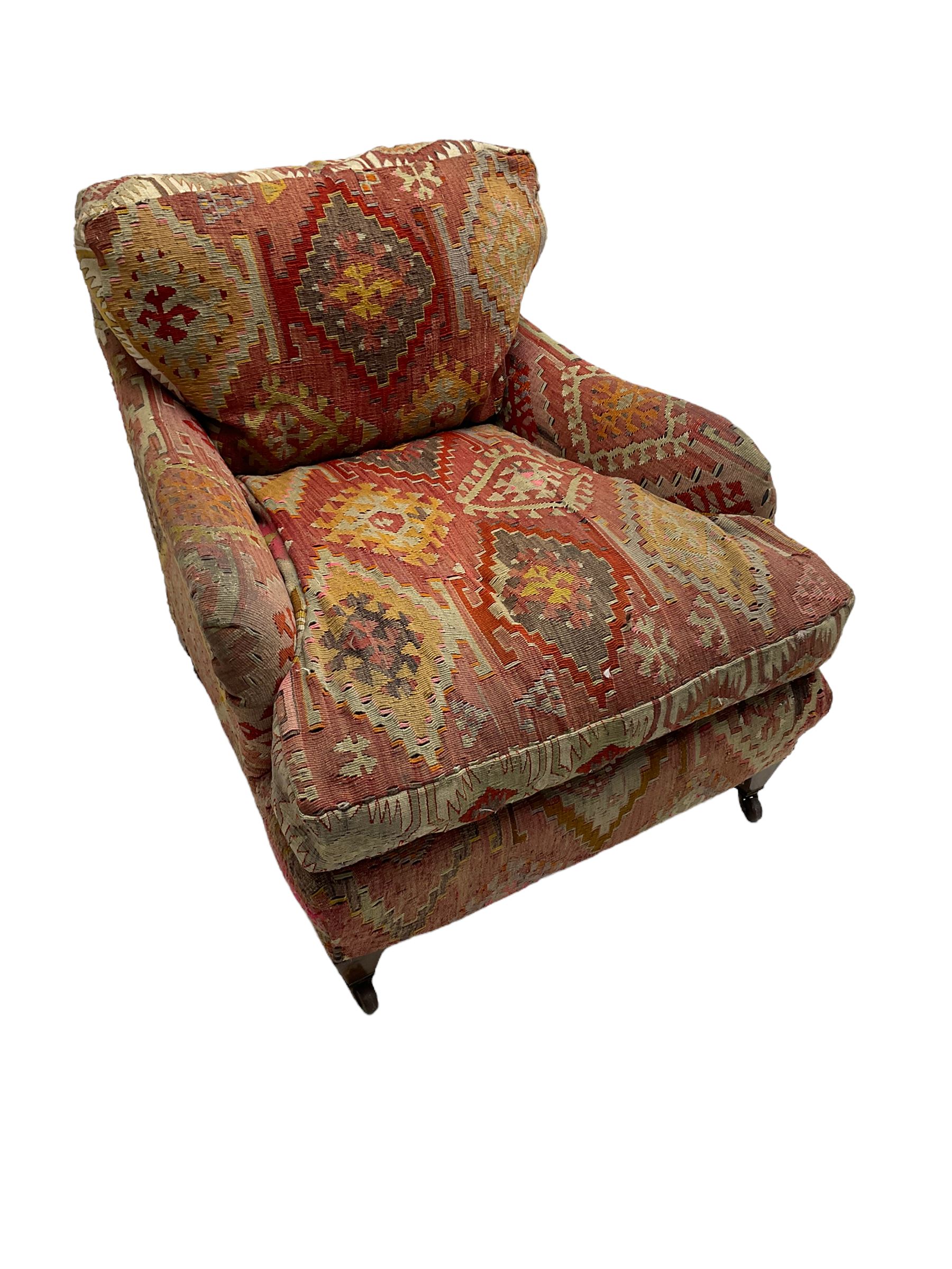 Early 20th century Howard style armchair, upholstered in Kilim fabric with sprung seat, hardwood frame, square tapering supports with brass and ceramic castors