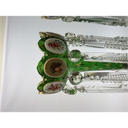 Pair of 19th century Bohemian green glass lustres, the castellated bowls decorated with overlaid panels of flowers and female portraits, upon tapering stems and overlaid spreading feet, heightened throughout with gilt, each supporting ten prismatic drops, H35cm